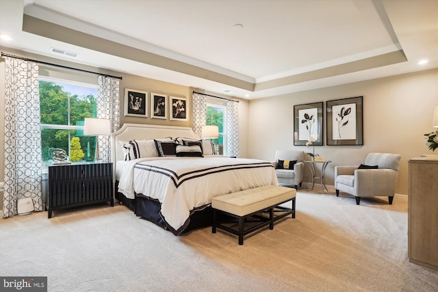 bedroom with light colored carpet, a raised ceiling, and multiple windows