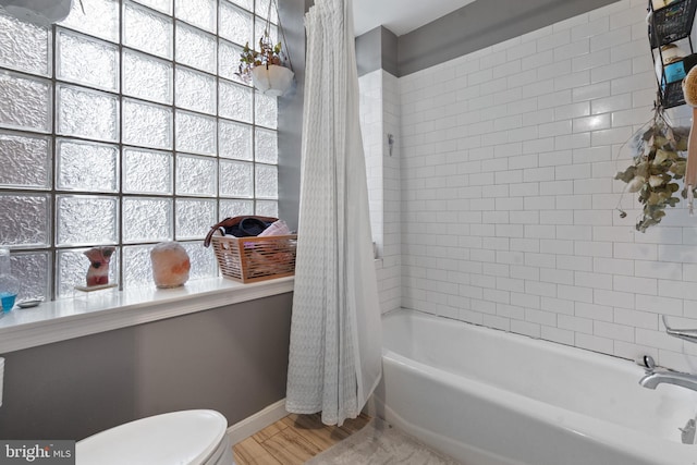 bathroom featuring hardwood / wood-style flooring, shower / tub combo with curtain, and toilet