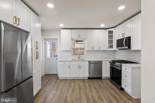 kitchen with tasteful backsplash, white cabinetry, appliances with stainless steel finishes, and sink