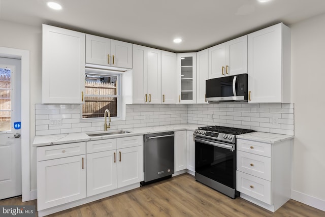 kitchen with light stone counters, sink, white cabinets, and appliances with stainless steel finishes