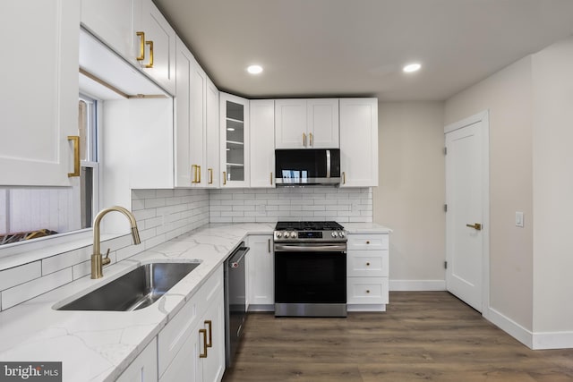 kitchen with white cabinetry, stainless steel appliances, light stone countertops, and sink