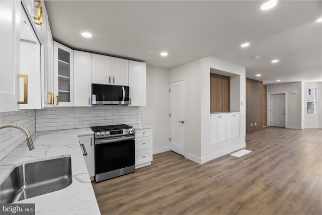 kitchen featuring sink, white cabinetry, stainless steel appliances, light stone counters, and tasteful backsplash