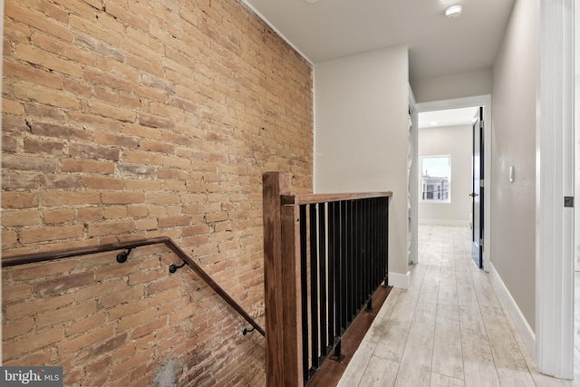 hallway with brick wall and hardwood / wood-style floors