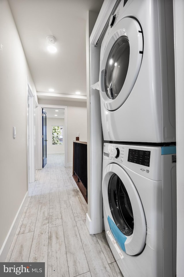 laundry area with stacked washer and dryer and light wood-type flooring