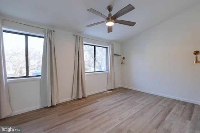 unfurnished room with a ceiling fan, visible vents, baseboards, lofted ceiling, and light wood-style floors