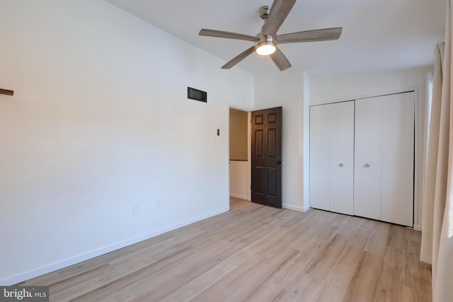 unfurnished bedroom with ceiling fan, lofted ceiling, a closet, and light wood-type flooring