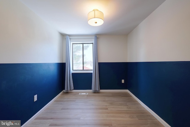 empty room featuring light wood-style flooring, visible vents, and baseboards