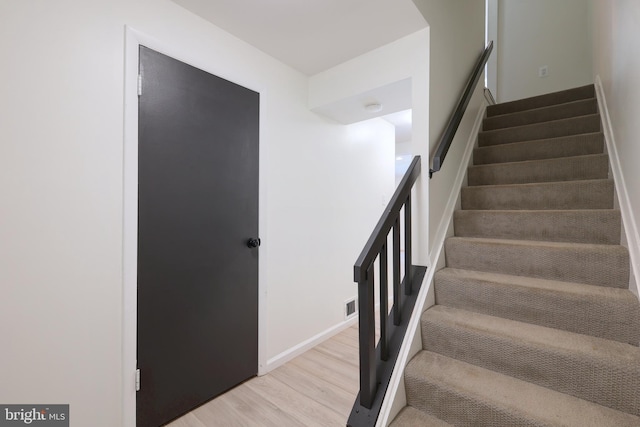 stairway with visible vents, baseboards, and wood finished floors