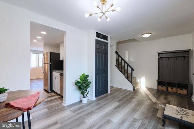 entrance foyer with stairs, baseboards, light wood-type flooring, and a chandelier