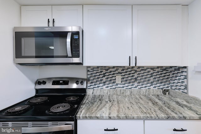 kitchen with stainless steel appliances, light stone countertops, decorative backsplash, and white cabinetry