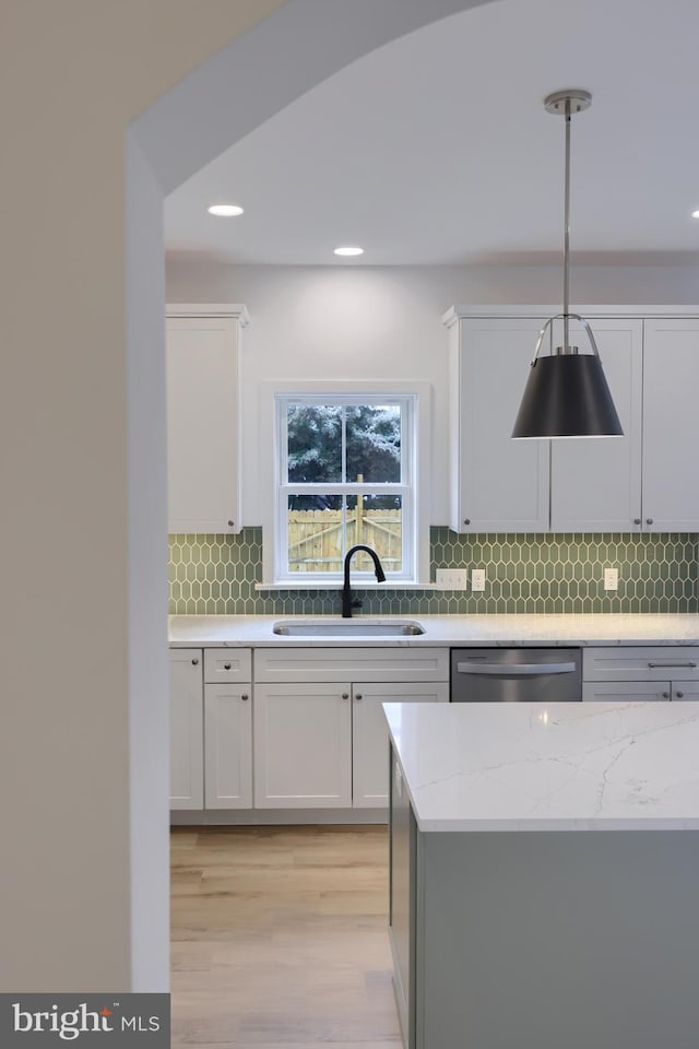 kitchen with dishwasher, sink, white cabinets, and decorative light fixtures