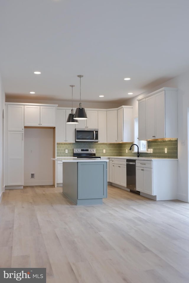 kitchen featuring stainless steel appliances, hanging light fixtures, and white cabinets