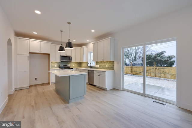 kitchen featuring hanging light fixtures, white cabinetry, appliances with stainless steel finishes, and sink