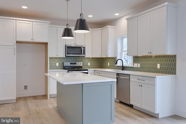 kitchen with hanging light fixtures, appliances with stainless steel finishes, a center island, and white cabinets