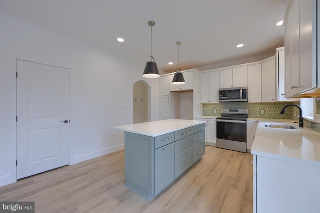 kitchen featuring sink, appliances with stainless steel finishes, white cabinetry, a kitchen island, and decorative light fixtures