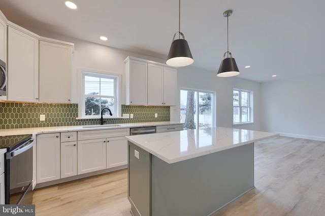 kitchen featuring sink, appliances with stainless steel finishes, white cabinetry, hanging light fixtures, and a center island