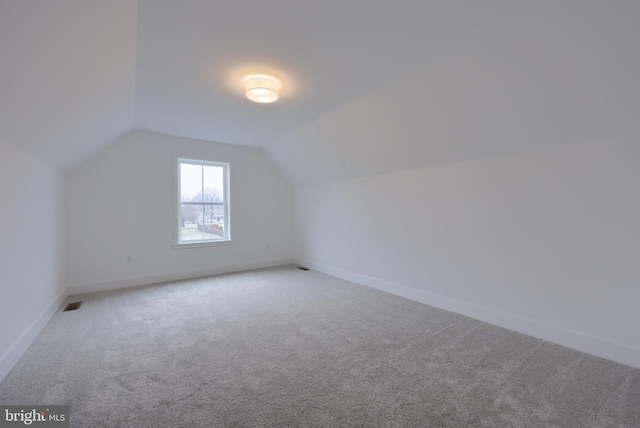 additional living space featuring carpet flooring and vaulted ceiling