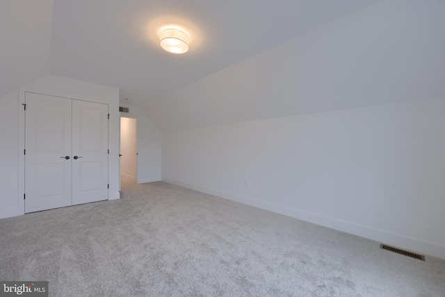 additional living space featuring lofted ceiling and light carpet