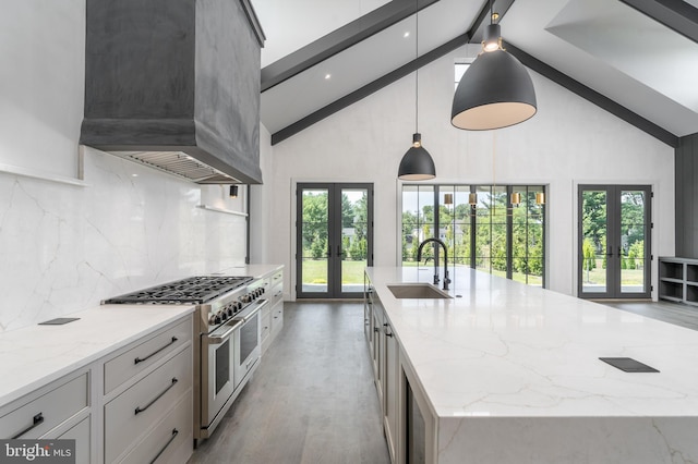 kitchen featuring a kitchen island with sink, french doors, decorative light fixtures, exhaust hood, and range with two ovens