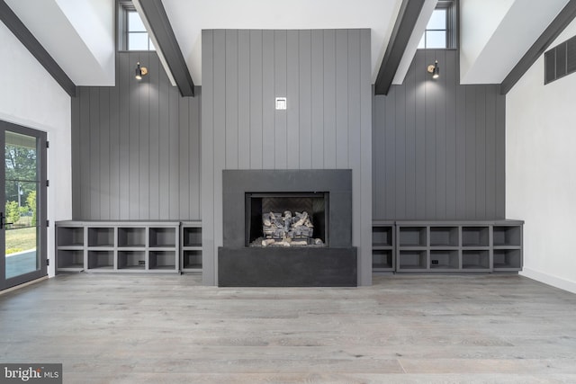 unfurnished living room featuring light hardwood / wood-style flooring, high vaulted ceiling, a large fireplace, and beamed ceiling