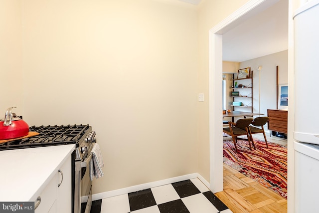 kitchen featuring white refrigerator, white cabinetry, and stainless steel gas stove