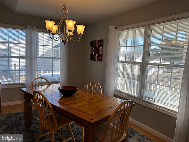 dining space with hardwood / wood-style floors and a notable chandelier