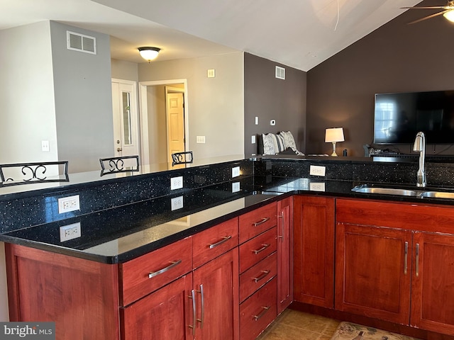 kitchen with sink, a breakfast bar area, kitchen peninsula, and dark stone counters