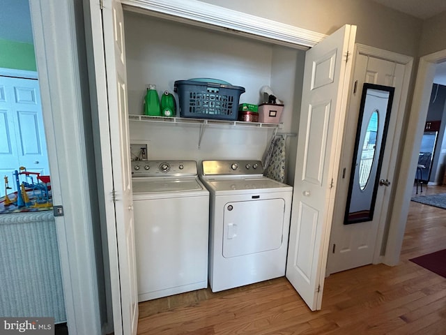 clothes washing area with separate washer and dryer and light hardwood / wood-style flooring