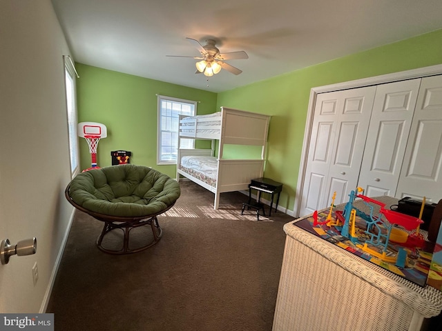 bedroom with ceiling fan, dark carpet, and a closet