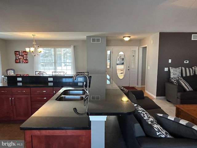 kitchen featuring tile patterned flooring, a chandelier, sink, and a center island with sink