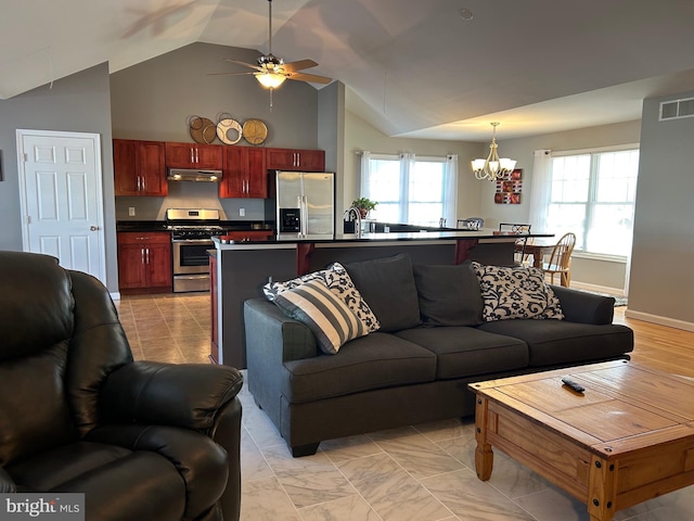 living room featuring vaulted ceiling, sink, and ceiling fan with notable chandelier