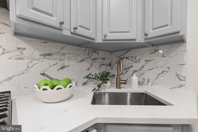 interior details with tasteful backsplash, sink, and white cabinets