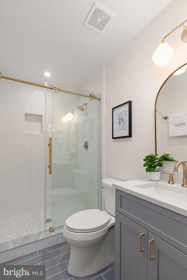 bathroom featuring vanity, toilet, and a shower with shower door