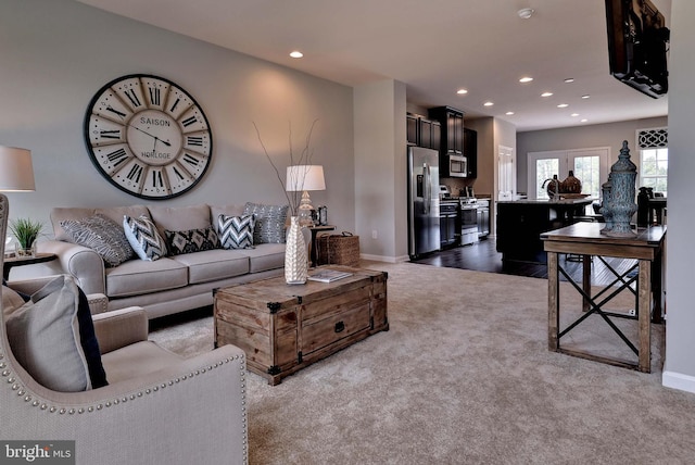 living room with recessed lighting, light colored carpet, and baseboards