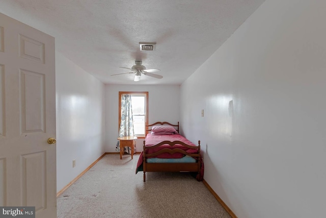 bedroom featuring ceiling fan, a textured ceiling, light carpet, visible vents, and baseboards