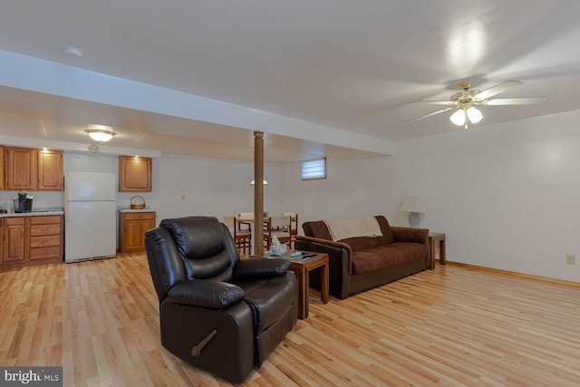 living room featuring baseboards, ceiling fan, and light wood finished floors