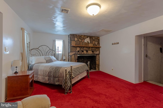 bedroom featuring visible vents, a stone fireplace, and carpet flooring