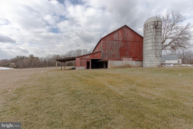 view of barn featuring a carport and a lawn