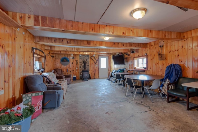 interior space with wood walls, a wood stove, and unfinished concrete floors