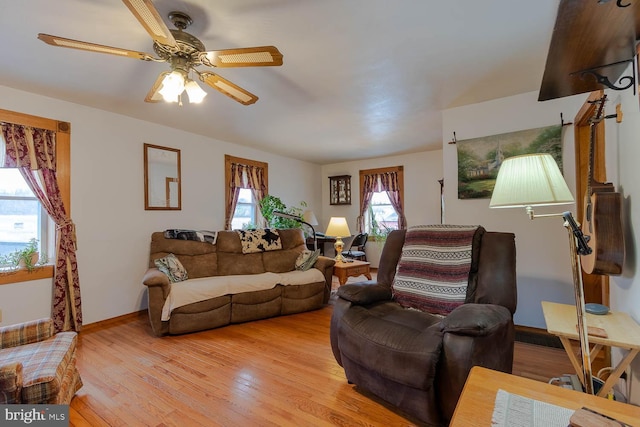 living room featuring light wood-style floors, baseboards, and a ceiling fan