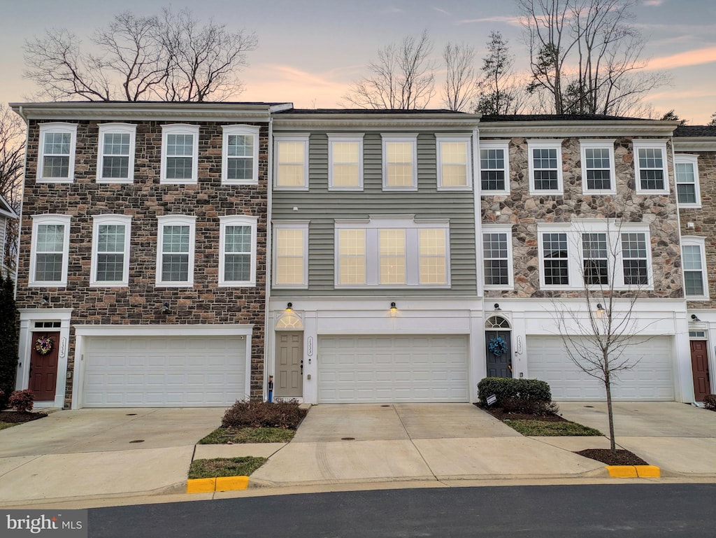 multi unit property featuring concrete driveway and an attached garage