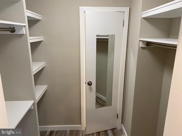 walk in closet with dark wood-type flooring