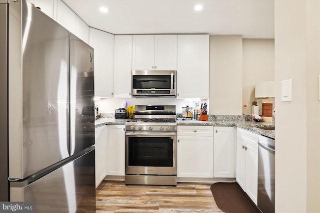 kitchen featuring stainless steel appliances, white cabinets, light stone counters, and light hardwood / wood-style floors