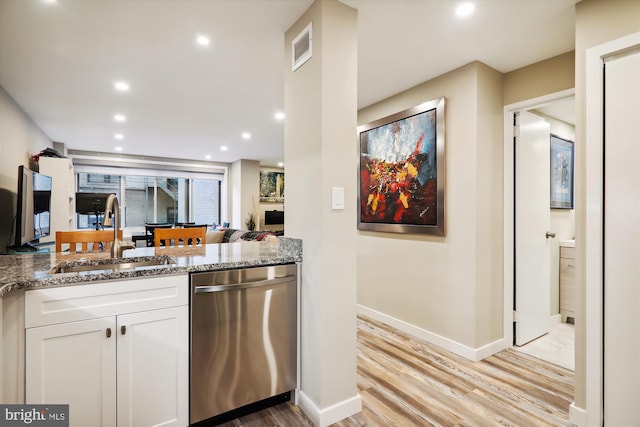 kitchen featuring white cabinetry, dishwasher, sink, light stone counters, and light wood-type flooring