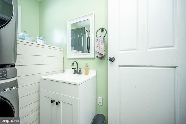 bathroom with stacked washing maching and dryer and vanity