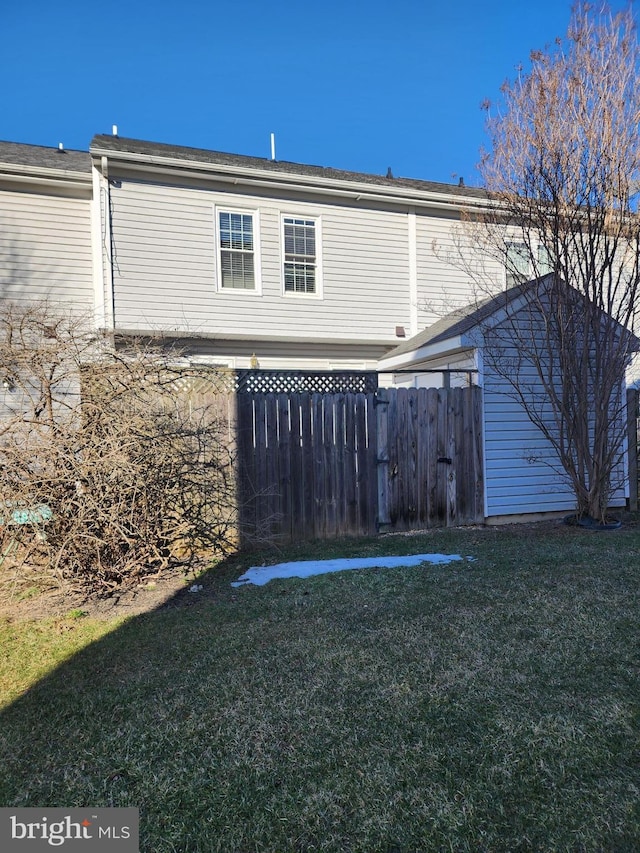 back of property featuring fence and a yard