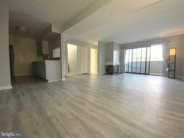 unfurnished living room with sink and light hardwood / wood-style flooring