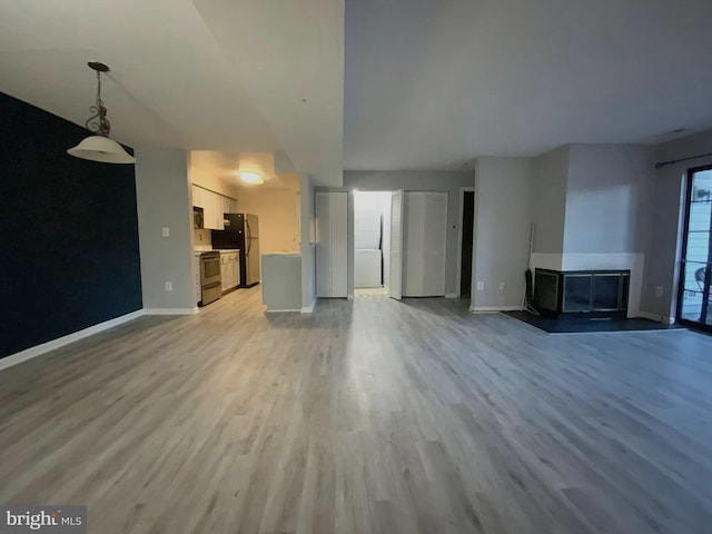 unfurnished living room with a multi sided fireplace and light wood-type flooring