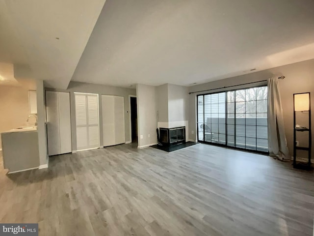 unfurnished living room with sink and light hardwood / wood-style flooring