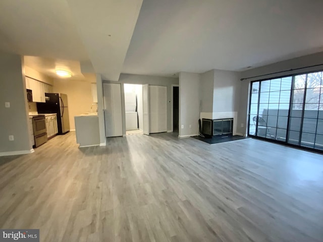 unfurnished living room featuring sink and light hardwood / wood-style flooring